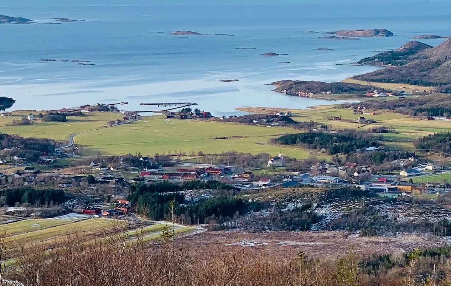 Panoramautsikt over kystlandskap med bygder, jorder og hav i bakgrunnen