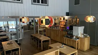 Lyst restaurantlokale med trebord, stoler og fargerike taklamper