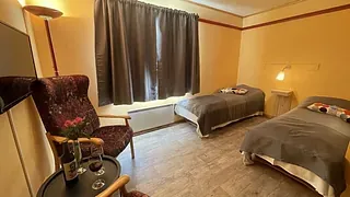 Dobbeltrom med to enkle senger, godstol, bord og dempet belysning